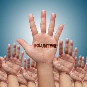 volunteer group raising hands against blue sky background